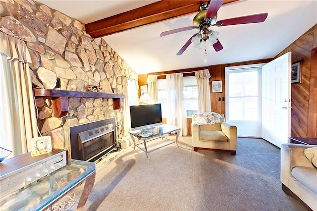 living room featuring lofted ceiling with beams, wood walls, a stone fireplace, and carpet floors