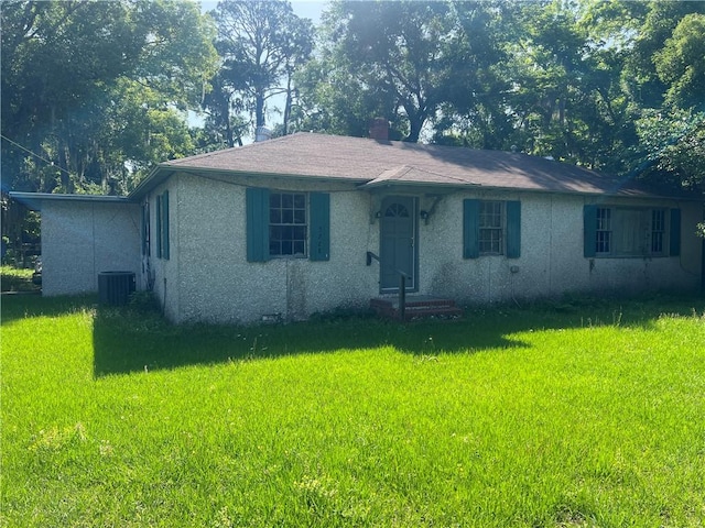 3228 Reynolds St, Brunswick, GA 31520 - view of front of home featuring a front yard, central AC unit, stucco siding, and a chimney