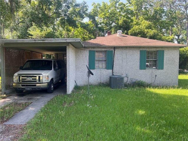3228 Reynolds St, Brunswick, GA 31520 - view of front of house with stucco siding, driveway, central AC unit, a carport, and a front lawn