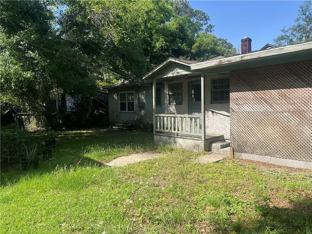 3228 Reynolds St, Brunswick, GA 31520 - view of side of home with covered porch, a chimney, and a yard