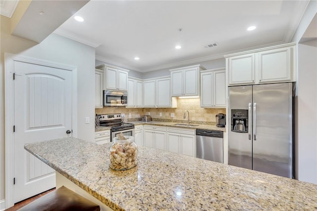 kitchen with white cabinets, stainless steel appliances, light stone countertops, and sink