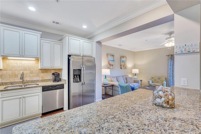 kitchen with ceiling fan, sink, appliances with stainless steel finishes, white cabinets, and ornamental molding