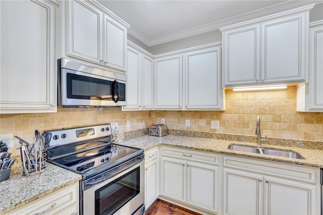 kitchen with light stone counters, stainless steel appliances, white cabinetry, and sink