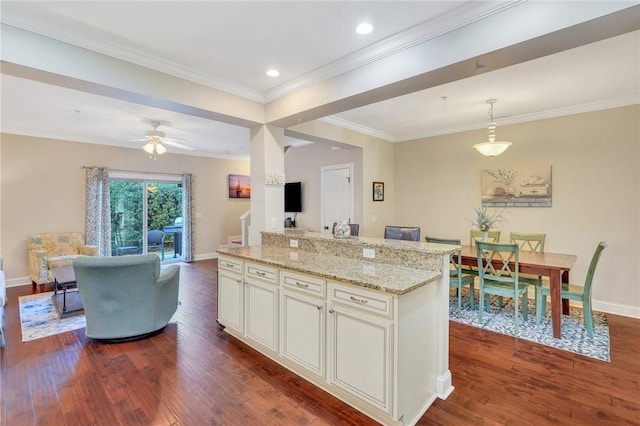 kitchen featuring dark hardwood / wood-style flooring, ceiling fan, crown molding, a center island, and hanging light fixtures