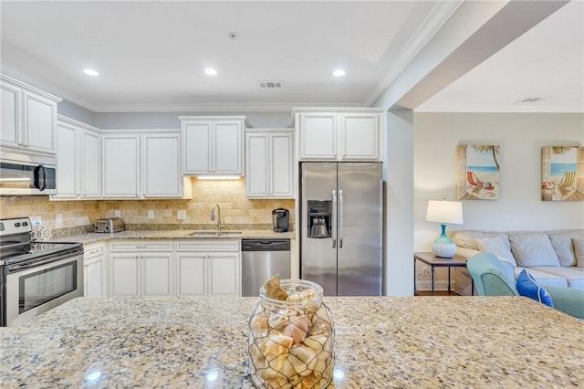 kitchen with light stone countertops, stainless steel appliances, crown molding, sink, and white cabinets