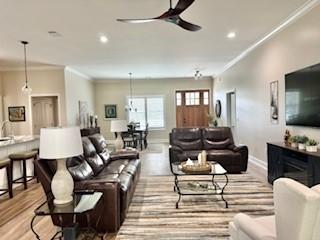 living room with ornamental molding, light hardwood / wood-style floors, and ceiling fan