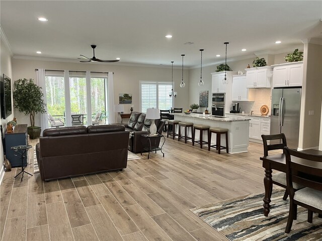 living room featuring crown molding, light hardwood / wood-style floors, and ceiling fan