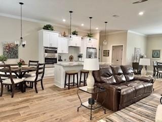 living room with ornamental molding and light hardwood / wood-style floors