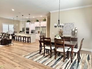 dining room featuring ornamental molding, an inviting chandelier, and light hardwood / wood-style floors