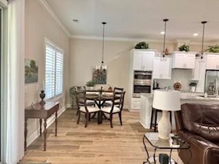 living room with ornamental molding, an inviting chandelier, and light wood-type flooring