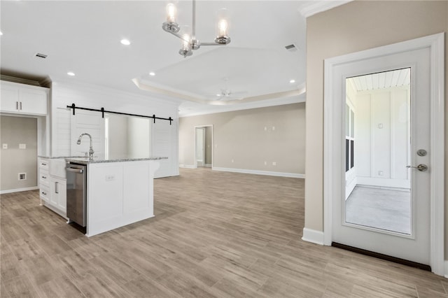 kitchen with white cabinetry, an island with sink, a barn door, light stone countertops, and stainless steel dishwasher