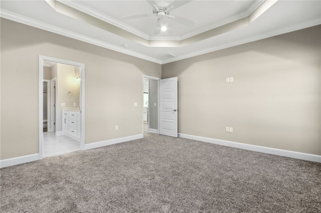 unfurnished bedroom with light colored carpet, ensuite bath, ornamental molding, ceiling fan, and a raised ceiling