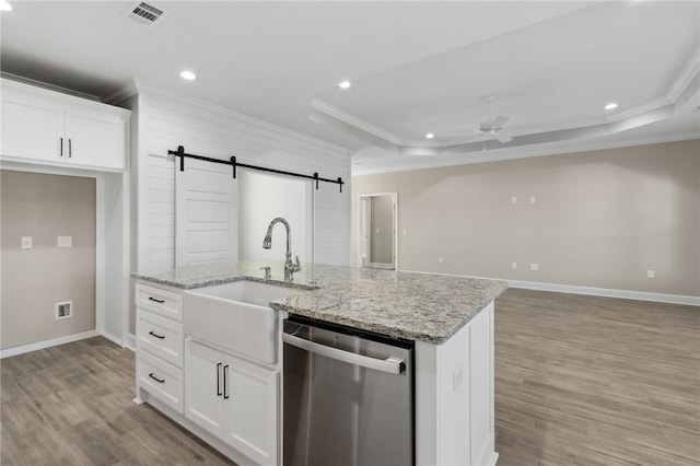 kitchen with white cabinetry, stainless steel dishwasher, a raised ceiling, and a barn door