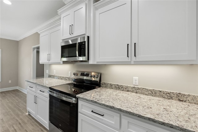 kitchen with white cabinetry, light hardwood / wood-style flooring, light stone countertops, ornamental molding, and appliances with stainless steel finishes