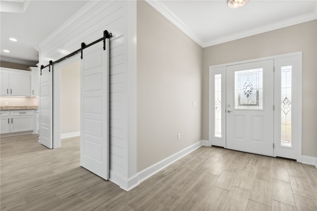 entryway with light wood-type flooring, a barn door, and ornamental molding