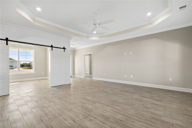 unfurnished room with a raised ceiling, light hardwood / wood-style flooring, ceiling fan, and a barn door