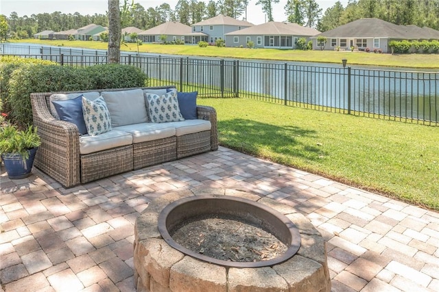 view of patio / terrace featuring a water view, a residential view, and an outdoor living space with a fire pit