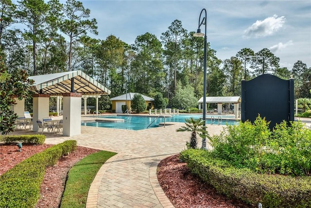 community pool with a gazebo, a patio area, and view of wooded area