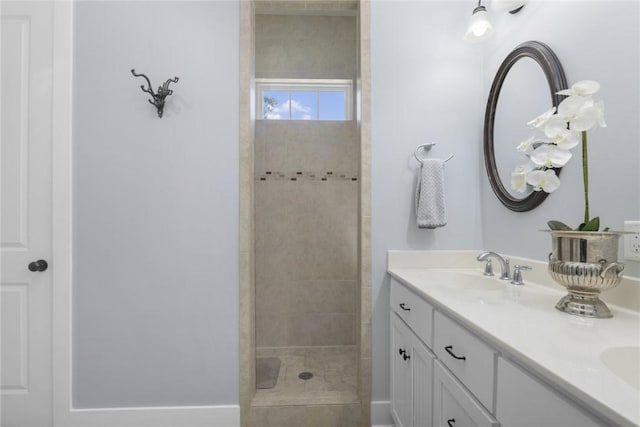 bathroom featuring a tile shower and double vanity