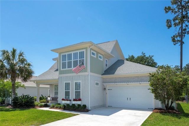 traditional-style home featuring an attached garage, a front yard, concrete driveway, and a shingled roof