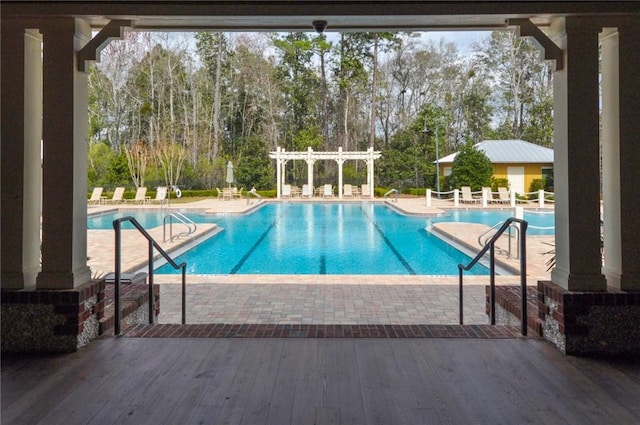 community pool featuring a pergola, view of scattered trees, and a patio area