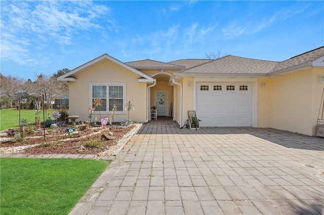 ranch-style home featuring a front lawn, decorative driveway, a garage, and stucco siding