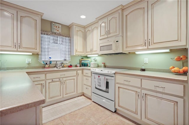 kitchen with light tile patterned floors, cream cabinetry, white appliances, and light countertops