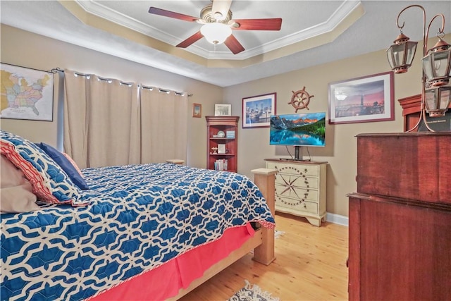 bedroom featuring a tray ceiling, wood finished floors, baseboards, and ornamental molding