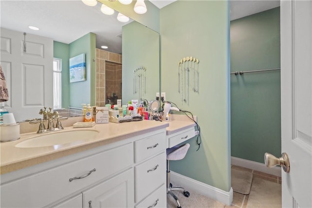 full bath featuring tile patterned floors, tiled shower, vanity, and baseboards