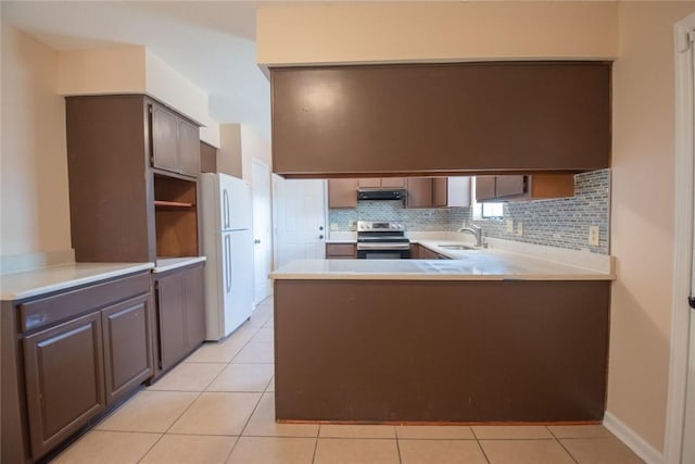 kitchen with a peninsula, electric range, freestanding refrigerator, a sink, and decorative backsplash