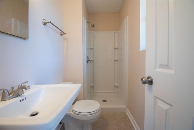 bathroom with a tile shower, tile patterned floors, toilet, and a sink