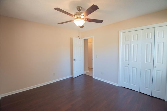 unfurnished bedroom featuring baseboards, dark wood-style flooring, a closet, and ceiling fan