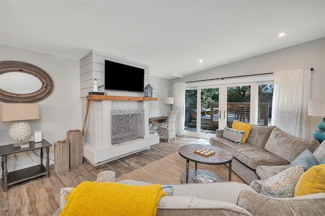 living room featuring hardwood / wood-style flooring, a tile fireplace, lofted ceiling, and french doors