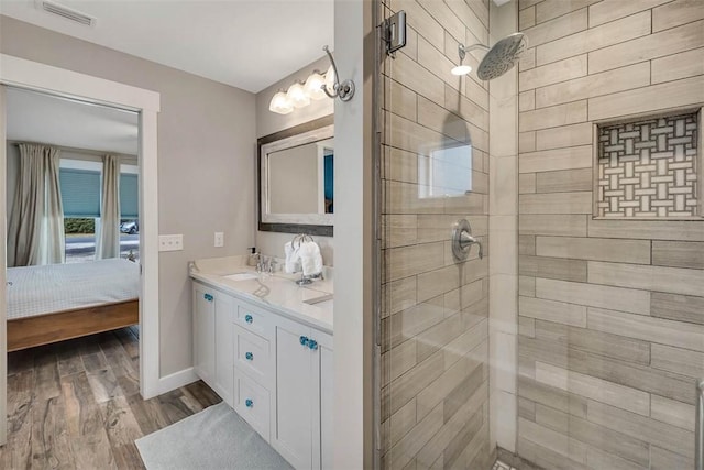 bathroom with vanity, wood-type flooring, and a tile shower