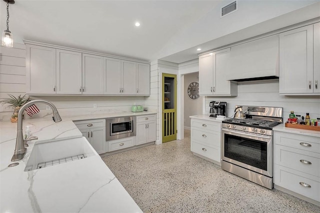 kitchen with decorative light fixtures, light stone countertops, white cabinets, and appliances with stainless steel finishes