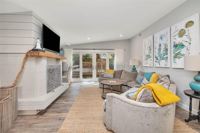 living room featuring lofted ceiling, hardwood / wood-style floors, and french doors