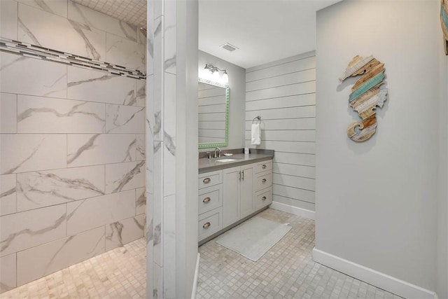 bathroom featuring vanity, a tile shower, and wooden walls