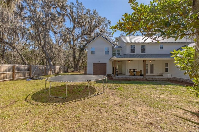 back of house featuring ceiling fan, a trampoline, a fenced backyard, a garage, and a patio