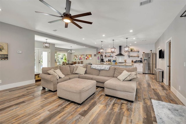 living room with visible vents, baseboards, recessed lighting, ceiling fan with notable chandelier, and wood finished floors