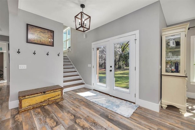 entrance foyer featuring stairway, wood finished floors, baseboards, an inviting chandelier, and french doors