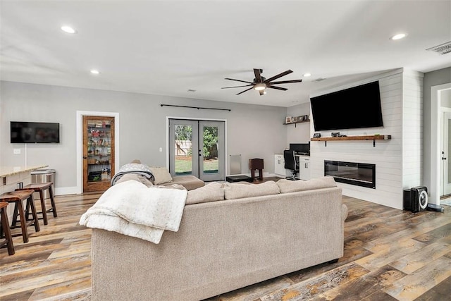 living room with visible vents, recessed lighting, wood finished floors, a glass covered fireplace, and a ceiling fan