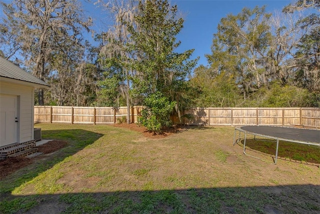 view of yard with a fenced backyard, cooling unit, and a trampoline