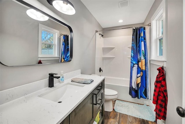 full bath featuring visible vents, toilet, shower / tub combo with curtain, wood finished floors, and vanity