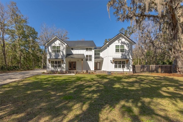 back of house featuring board and batten siding, fence, a lawn, metal roof, and a standing seam roof