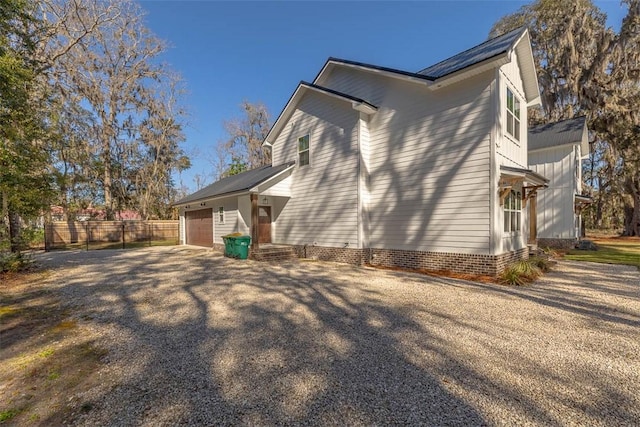 view of home's exterior with an attached garage, fence, and driveway