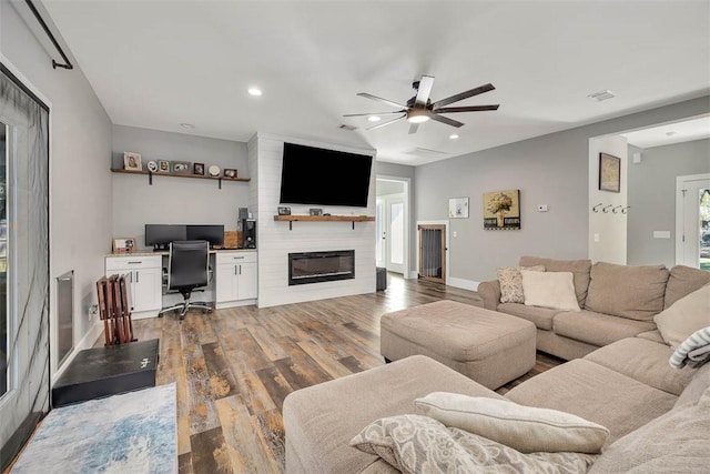 living area with a large fireplace, recessed lighting, wood finished floors, and ceiling fan