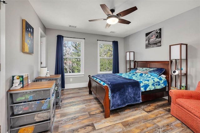 bedroom featuring visible vents, baseboards, wood finished floors, and a ceiling fan