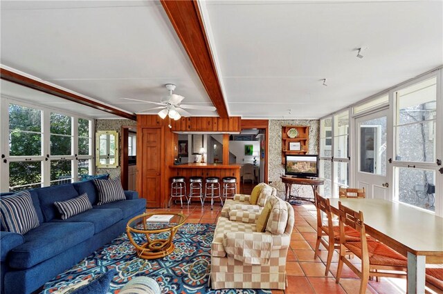 tiled living room with ceiling fan and beam ceiling