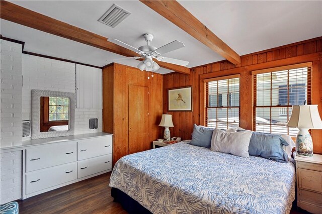 bedroom with beam ceiling, multiple windows, wooden walls, and ceiling fan