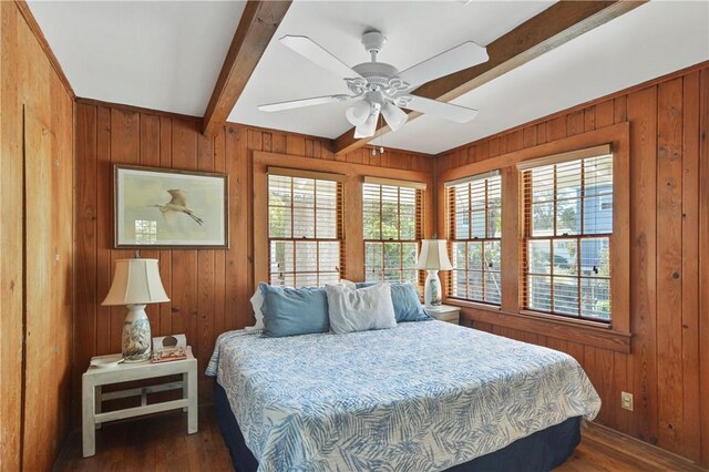 bedroom featuring ceiling fan, wood walls, beam ceiling, and dark wood-type flooring